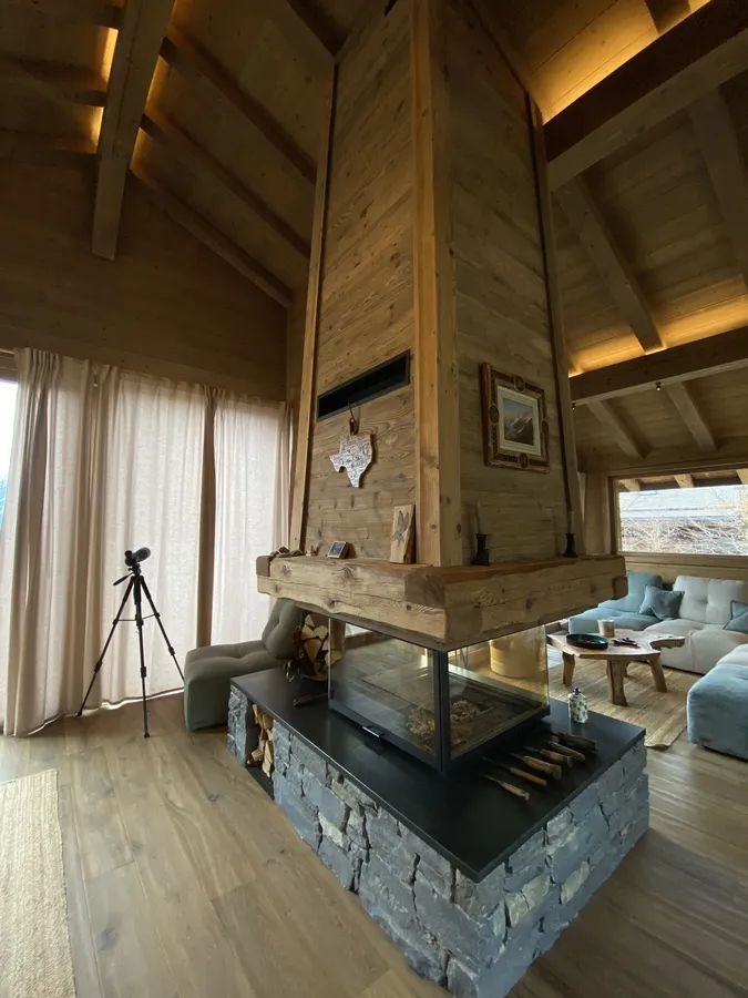 Cheminée centrale et éclairage de charpente dans un chalet